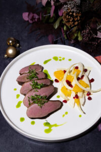 Ente mit Korianderöl serviert auf weißem Teller und Fenchel Orangen Granatapfel Salat