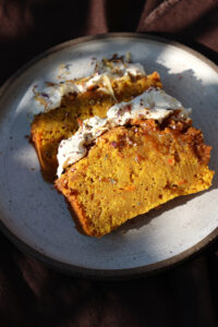 Herbstlicher Pumpkin Spice Kuchen mit Zimt Swirl und Frischkäse Frosting dekoriert mit Orangenzesten und getrockneten Blüten
